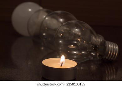 Burning candle on the background of light bulbs. Blackout due to war in Ukraine - Shutterstock ID 2258130155