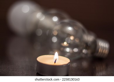 Burning candle on the background of light bulbs. Blackout due to war in Ukraine - Shutterstock ID 2258130163