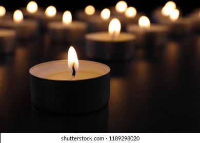 Burning candle on table in darkness, closeup with space for text. Funeral symbol