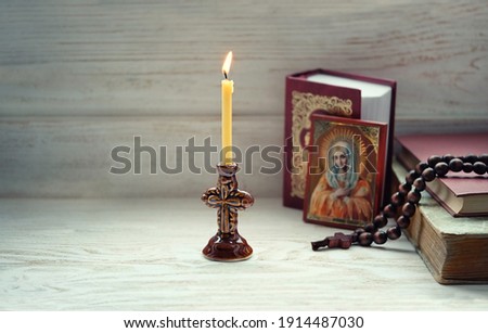 burning candle, orthodox icon, rosary beads, bible books on wooden table. concept of faith in God. Symbol of orthodox Church, lent, religion. Assumption of Mary day