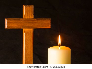 Burning candle shining on crucifix
