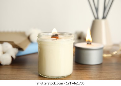 Burning Candle With Wooden Wick On Table