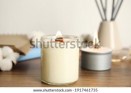 Burning candle with wooden wick on table