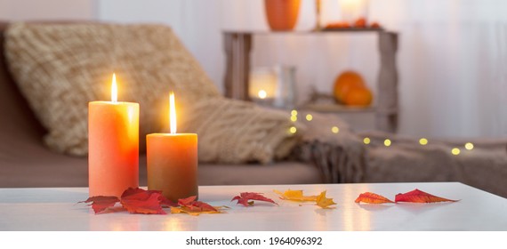 Burning Candles With Autumn Decor On White Table At Home