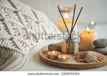Burning candles on bamboo tray, cozy home atmosphere. Relaxation, detention zone in the living or bedroom. Stones, sea shells as decor. Apartment natural aroma diffusor with ocean breeze fragrance. 
