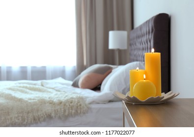 Burning Candles On Bedside Table In Bedroom