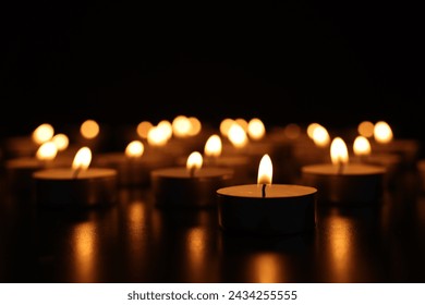 Burning candles on dark surface against black background, closeup - Powered by Shutterstock