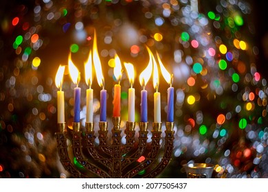 Burning candles on menorah for Hanukkah on defocus color lights background. Jewish holiday.