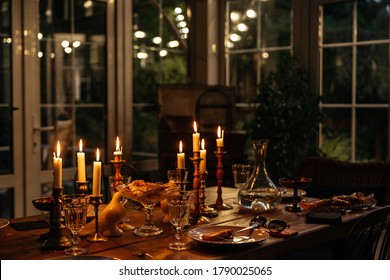 Burning Candles On The Table In A Cozy House In The Evening Decorate The Table With Food. Evening Romantic Dinner At The Restaurant.