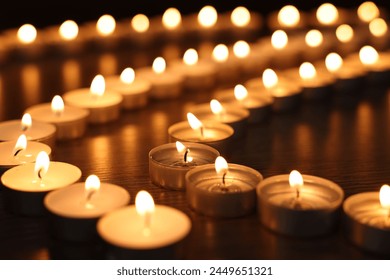 Burning candles on wooden table in darkness, closeup - Powered by Shutterstock