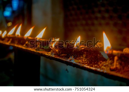 Burning candles in a row, darkness inside temple. Kathmandu, Nepal, Asia