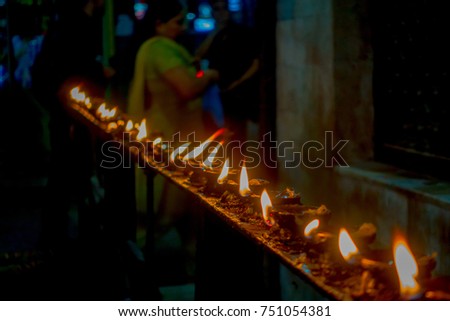 Burning candles in a row, darkness inside temple. Kathmandu, Nepal, Asia