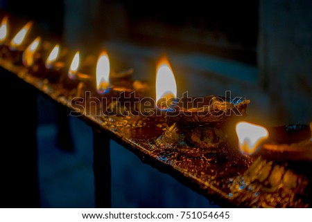 Burning candles in a row, darkness inside temple. Kathmandu, Nepal, Asia