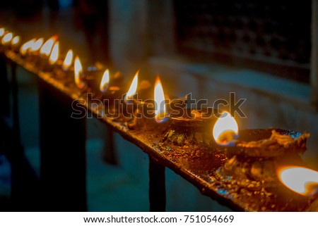 Burning candles in a row, darkness inside temple. Kathmandu, Nepal, Asia
