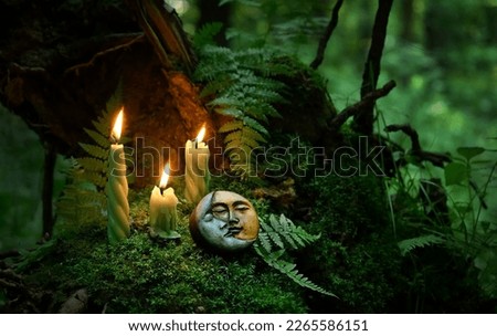 Burning candles and symbolic moon amulet in forest, abstract dark natural background. Witchcraft, magic practice. esoteric spiritual ritual for wiccan Litha sabbat. fairytale atmosphere.
