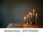 burning candles in vintage candlesticks on dark background