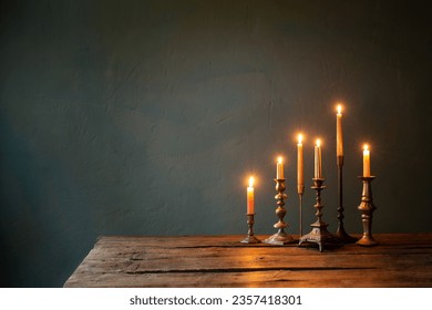burning candles in vintage candlesticks on dark background