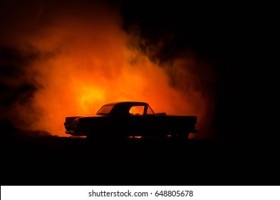 Burning Car On A Dark Background. Car Catching Fire, After Act Of Vandalism Or Road Indicent. Burning Vintage Car Nightshot