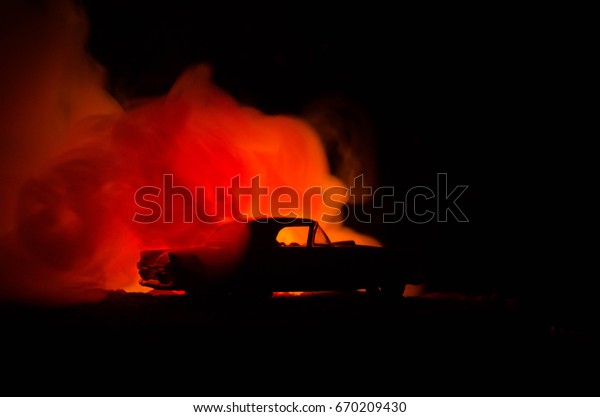 Burning\
car on a dark background. Car catching fire, after act of vandalism\
or road indicent. Burning vintage car\
nightshot