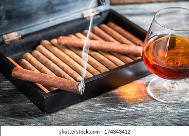 Burning Cigar On Humidor And Cognac