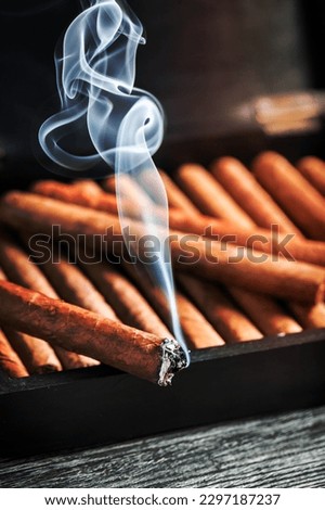 Burning cigar on wooden humidor full with cigars