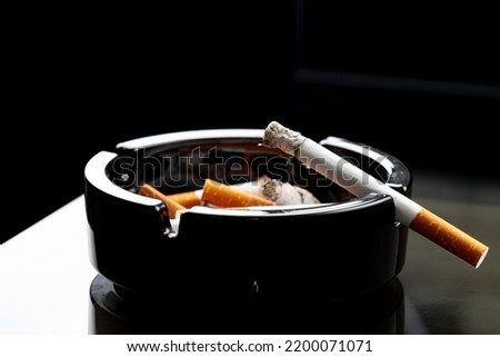 Burning cigarette in a black ash tray