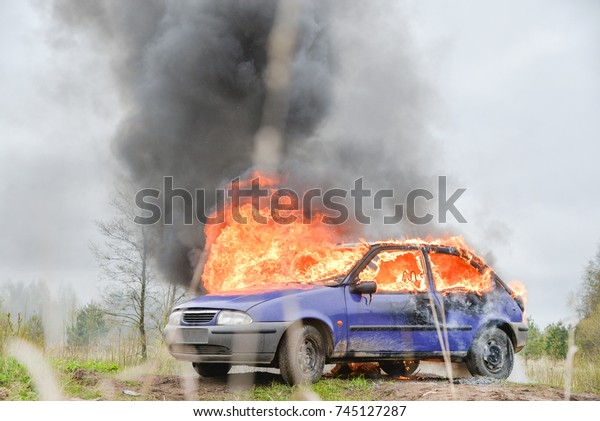 Burning and\
crashed car after explosion. Accident on street at countryside.\
Fire fighters prepare to attack a propane fire. No one is injured.\
Artificially created set for film\
making