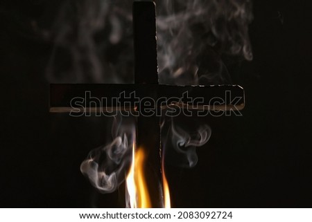 Burning cross with smoke in dark night