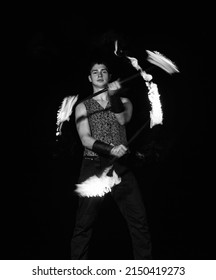 Burning energy. Handsome man juggle flaming batons. Fire juggling. Fire energy. Energetic twirling. Flame and sparks. Night performance. Amusement show. Light up and juggle