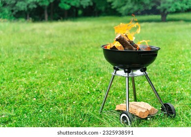 Burning fire flame in round grill bbq. Cooking outdoors in a meadow. Background with copy space. - Powered by Shutterstock