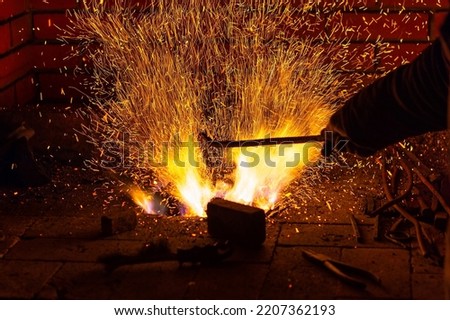 Burning fire with sparks and red-hot metal ready to be forged in a forge. Blacksmithing manufacture.