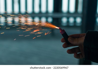 Burning Firecracker with Sparks. Guy Holding a Petard in a Hand. Loud and Dangerous New Year's Entertainment. Hooliganism with Pyrotechnics. Noise of Firecrackers in Public Places - Shutterstock ID 2220569967