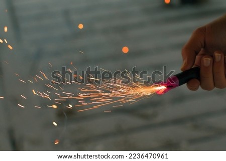 Burning Firecracker with Sparks. Guy Holding a Petard in a Hand. Loud and Dangerous New Year's Entertainment. Hooliganism with Pyrotechnics. Noise of Firecrackers in Public Places