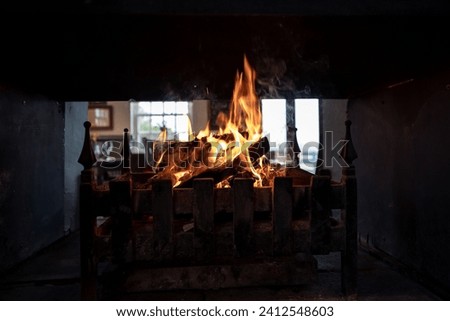 A burning fireplace in a traditional setting, with smoke billowing out of the open doors