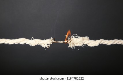 Burning Frayed Rope At Breaking Point On Gray Background