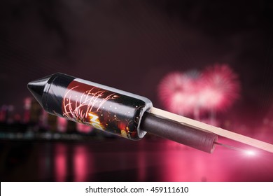 A Burning Fuse From A Pyrotechnics Rocket In Front Of A Red Shining Blurry City With Fireworks Explosion.