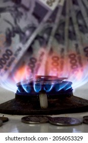 Burning Gas Stove Burner And Uzbek Money - Sum Banknotes. Pay For Natural Gas, Bill, Tariff. Growing Tariffs For Gas. Pile Of Coins And Burning Fire Gas Stove Hob And Money