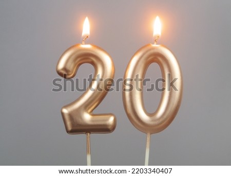 Burning gold birthday candles on gray background, number 20