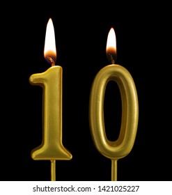 Burning golden birthday candles isolated on black background, number 10
