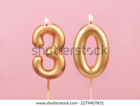 Burning golden birthday candles on pink background, number 30