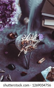 Burning herbs on a witch's altar for a magical ritual among crystals and black candles.