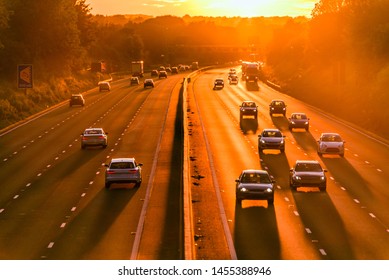 Burning Hot Sunset On Uk Motorway With Long Shadows Of Moving Car Traffic In England