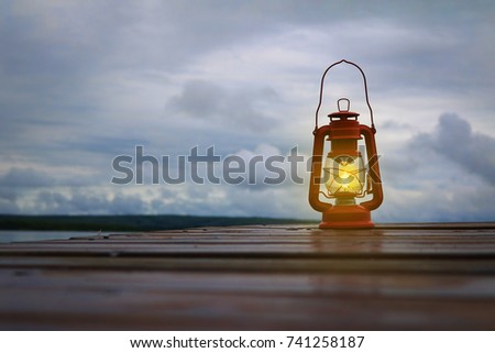 Burning lantern on a dock at a lake in the twilight 