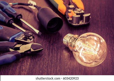 burning light bulb and socket and other electrician tools are on the table
