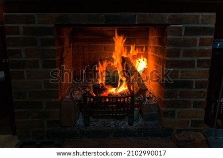 A burning log fire in an old brick fireplace