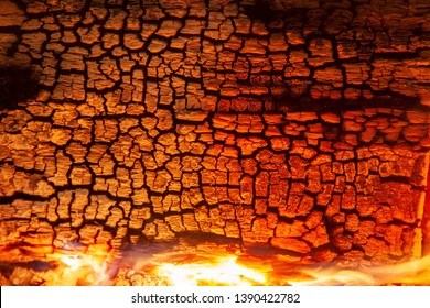 Burning log of wood close-up as abstract background. The hot embers of burning wood log fire. Firewood burning on grill. Texture fire bonfire embers. Smoldering fire