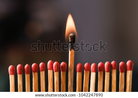 Burning match among others on black background. Difference and uniqueness concept