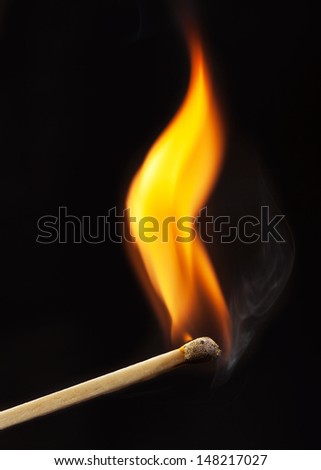 burning matchstick on black background