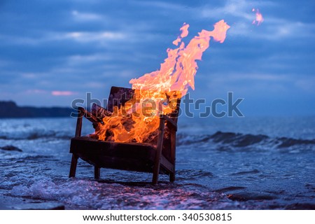 Burning old armchair on the seashore