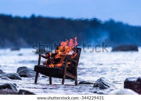 Burning old armchair on the seashore